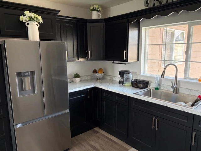 The same kitchen after: dark shaker cabinets, quartz counters and stainless appliances
