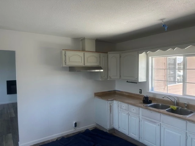 The kitchen before: dated cream cabinets, a scalloped valance and worn laminate counters