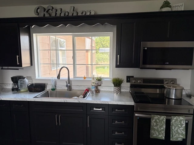 Dark shaker kitchen with quartz counters and a window over the sink